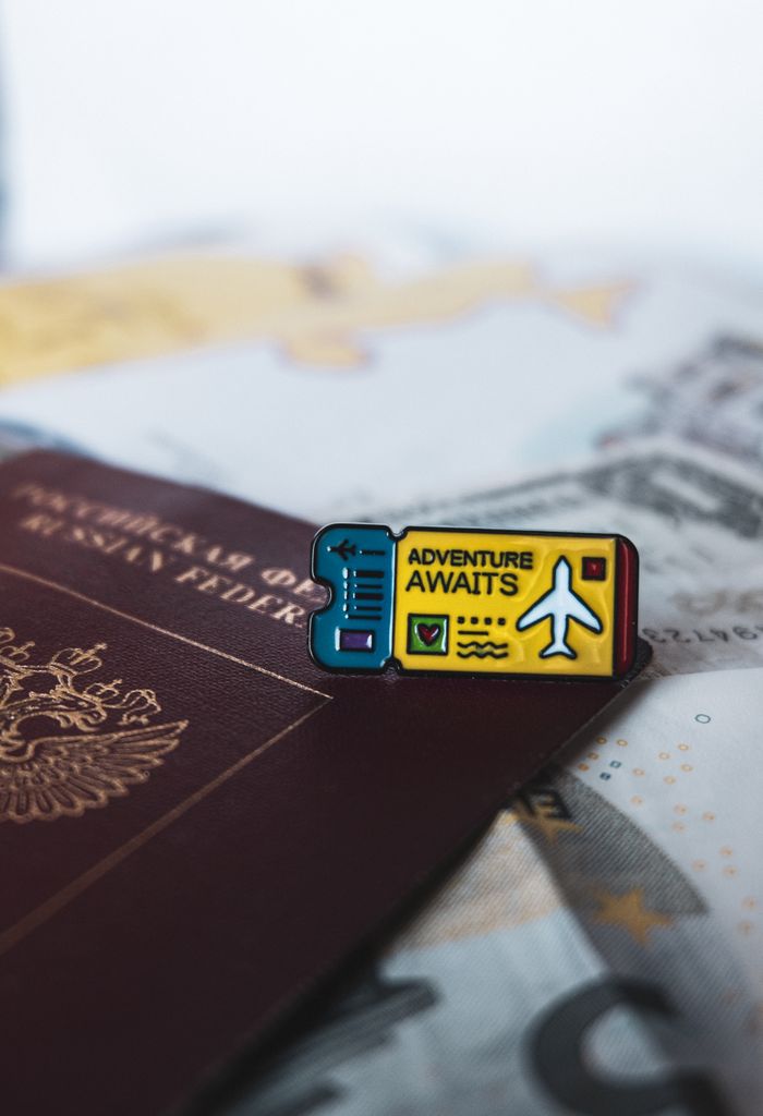 About A Russian passport with an 'Adventure Awaits' pin symbolizes travel and exploration.